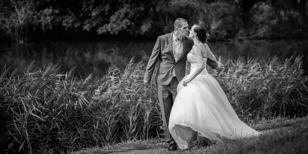 Novomanželé u rybníka ba černobílé fotografii.